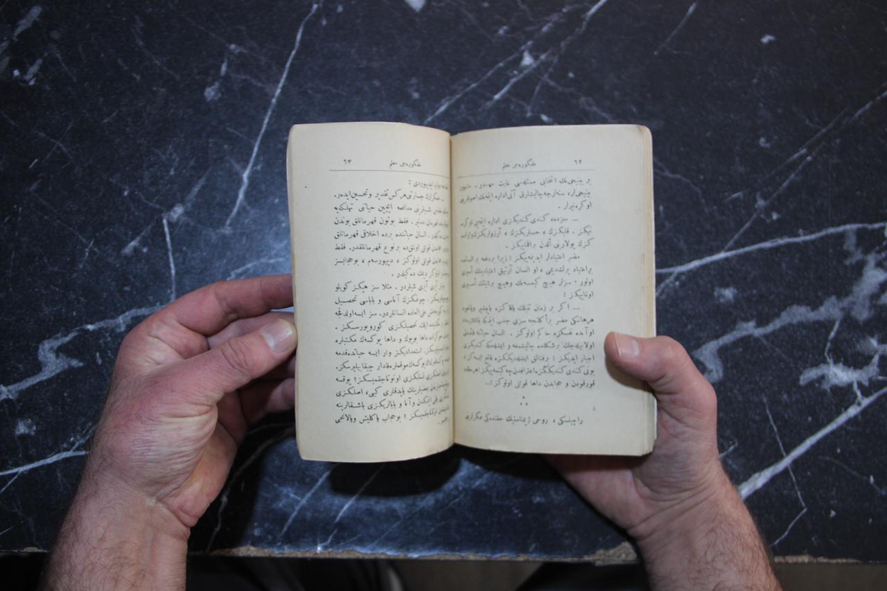Pages of a rare 1928 edition of Grigory Petrov's The Idealist Teacher, printed in Ottoman Turkish using the Arabic-based script, are displayed at a secondhand bookstore in Erzurum, Türkiye, Oct. 21, 2026. (IHA Photo)