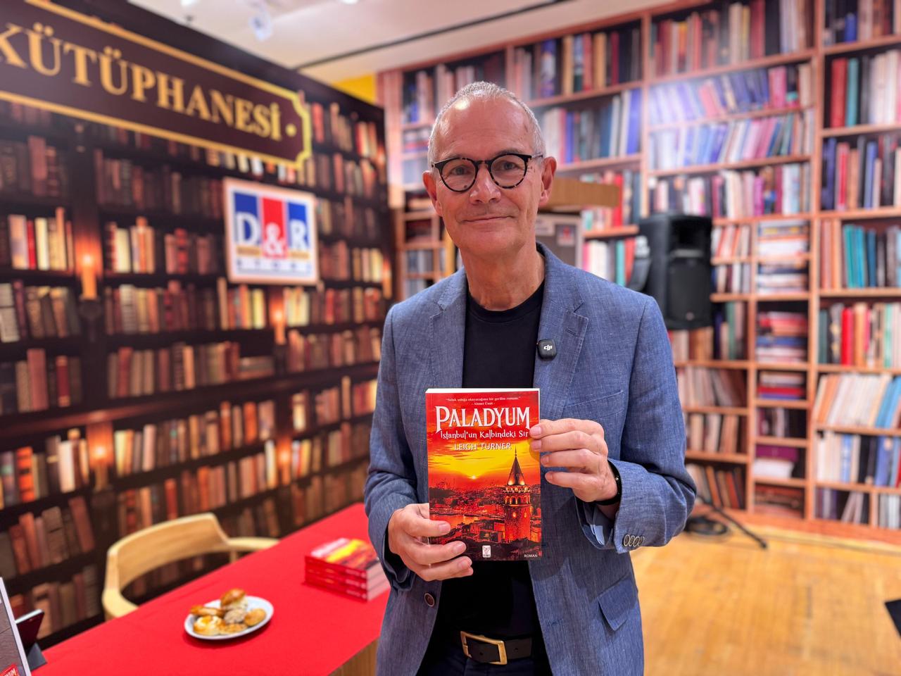 British author and former diplomat Leigh Turner poses with the Turkish edition of his new thriller, Palladium: The Secret in the Heart of Istanbul, at D&R Kanyon in Istanbul, Türkiye, Oct. 20, 2026. (AA Photo)