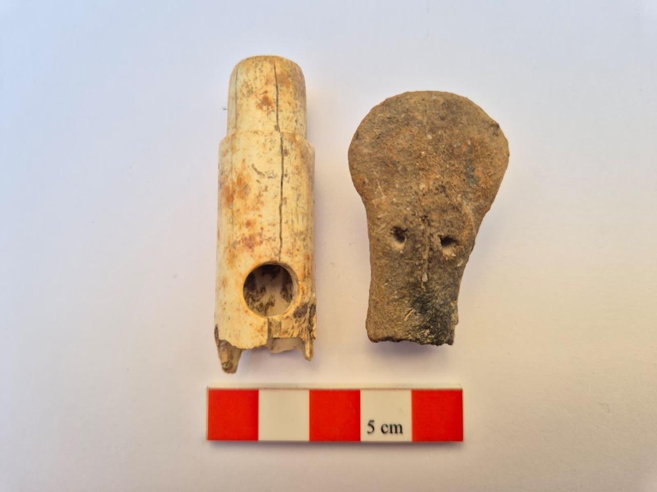 A bone flute dating back to the Archaic period and a human-shaped idol head from the Early Bronze Age are displayed alongside a measuring scale following their discovery at ancient Troy. (Photo via Türkiye's Ministry of Culture and Tourism)