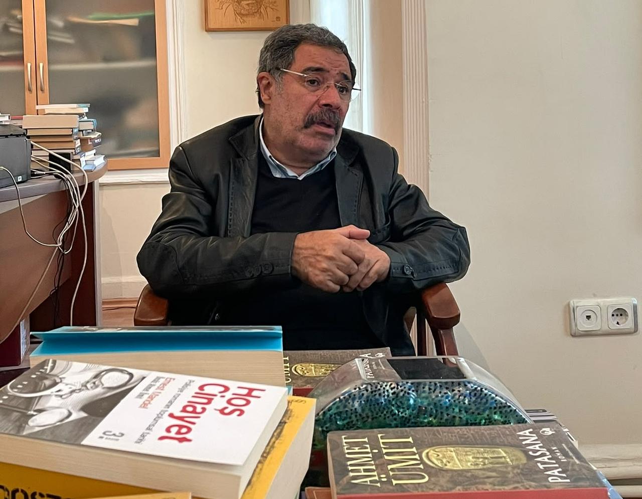 Turkish novelist Ahmet Umit speaks during an interview at his office in Istanbul, with copies of his works, including Patasana, displayed in the foreground, Türkiye, Oct. 19, 2026. (Photo by Türkiye Today team)