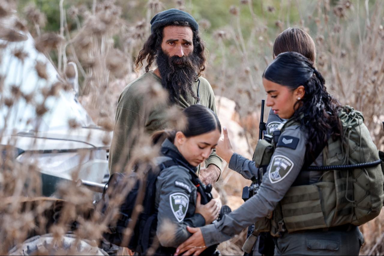 An Israeli settler stands next to Israeli border guards entering an olive grove as Palestinian farmers and foreign activists (unseen) gather to pick olives in the village of Turmus Ayya, northeast of Ramallah in the Israeli-occupied West Bank, on October 21, 2026. (AFP Photo)