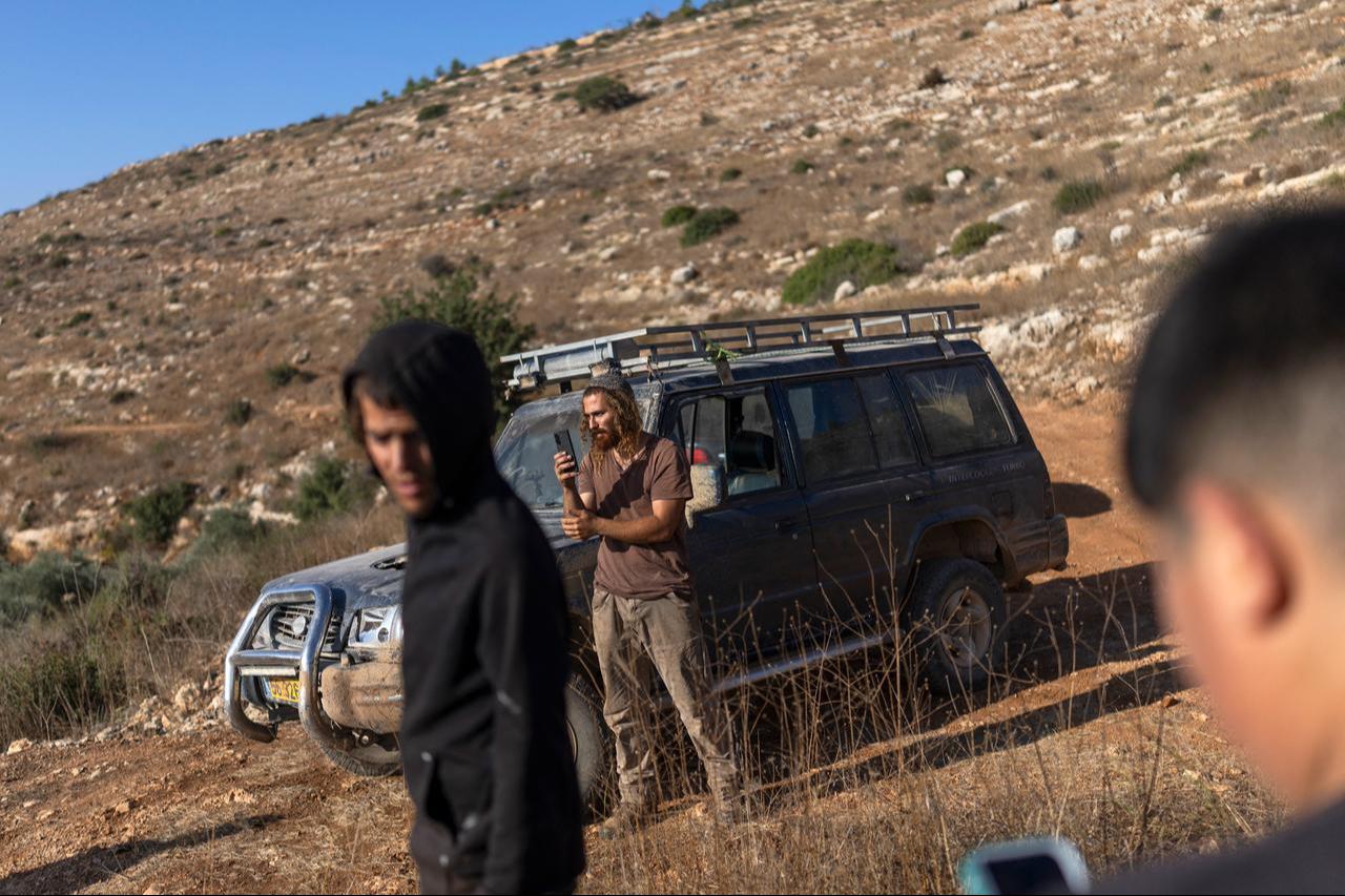 Israeli settlers gather as Palestinian farmers harvest their olive trees in the Israeli-occupied West Bank village of Deir Abu Mashal on October 19, 2026. (AFP Photo)