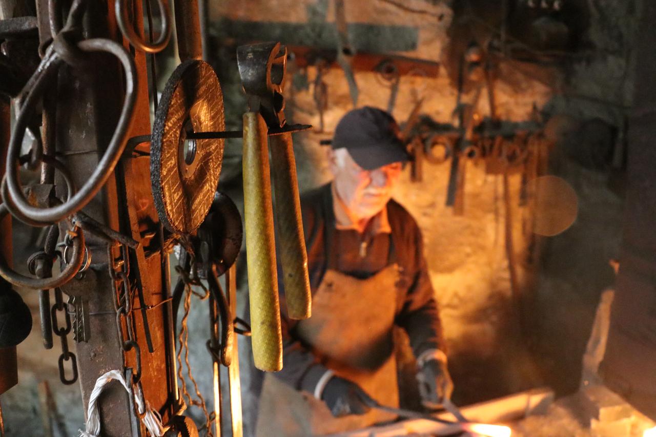 Blacksmith Remzi works with metal tools near a glowing forge in his workshop in Türkiye, Oct. 23, 2026. (AA Photo)