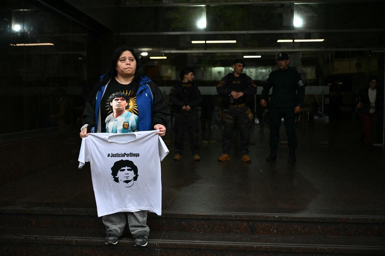 A supporter of Argentine football legend Diego Maradona holds a shirt bearing his portrait and the slogan "Justice for Diego" outside the courthouse during the trial over his death in San Isidro, Buenos Aires Province, Argentina, Oct. 21, 2026. (AFP Photo)