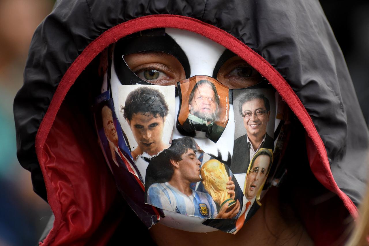 A demonstrator wears a mask featuring images of public figures, including Argentine football legend Diego Maradona, during an anti-government protest in Bogota, Colombia, Oct. 14, 2026. (AFP Photo)