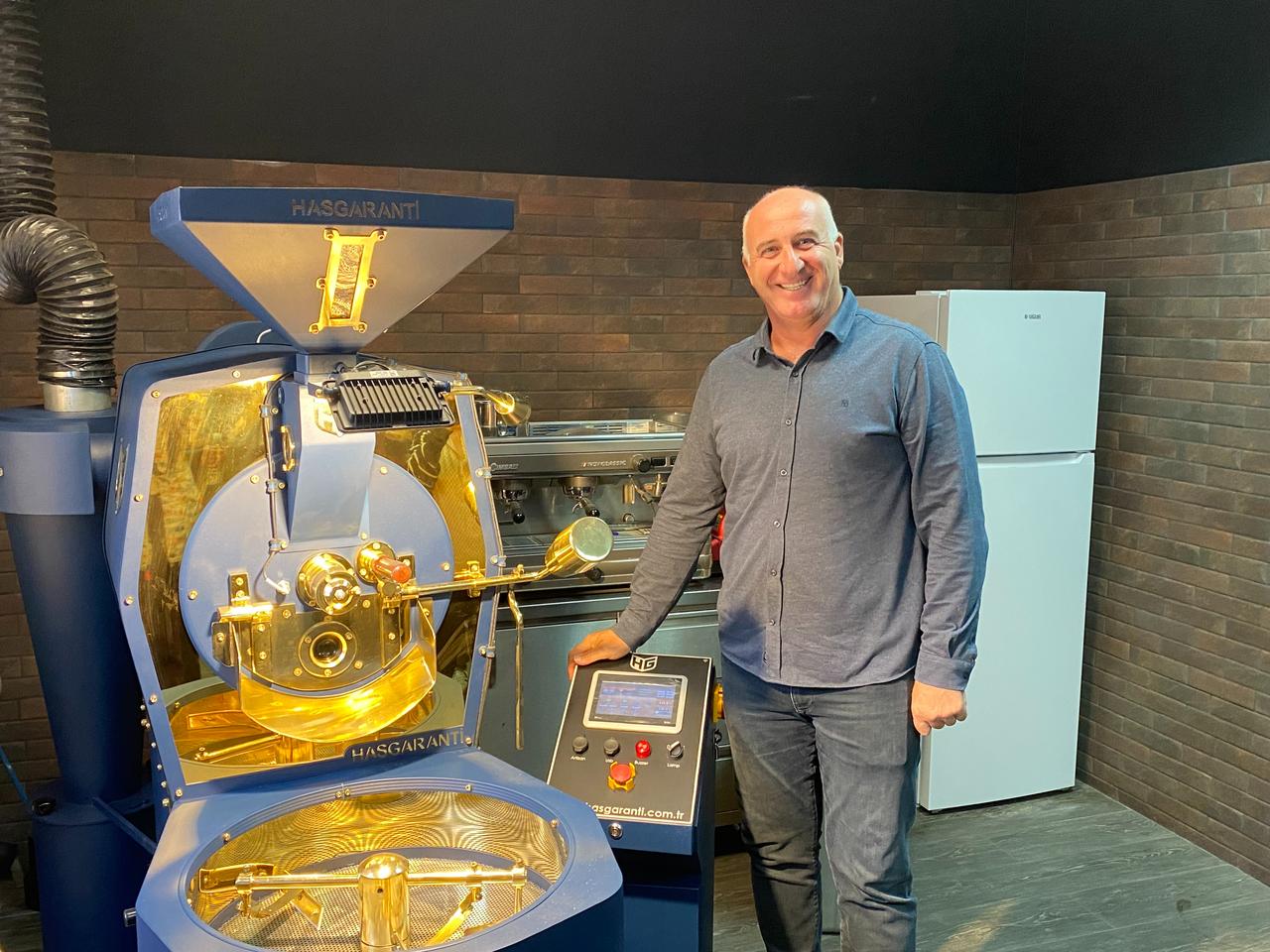 Mujdat Aydin, CEO and co-owner of Hasgaranti Coffee Roasters & Grinders, next to one of his machines during a press Q&A at his factory in Izmir, Türkiye. (Photo via Türkiye Today/ Feiza Jdidi)