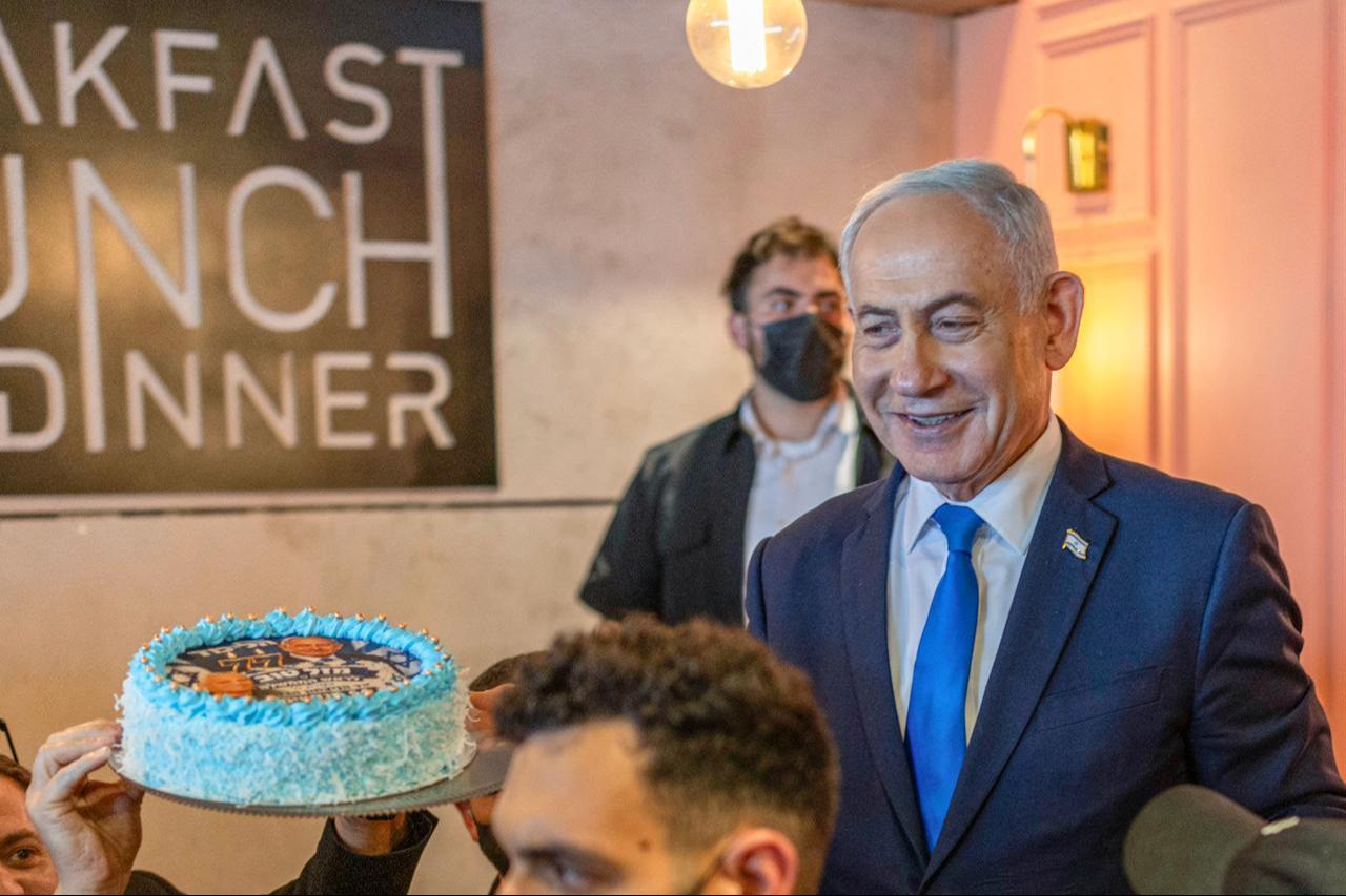 Israel's Prime Minister Benjamin Netanyahu (R) interacts with supporters who brought him a cake to celebrate his 77th birthday during a Likud Party meet-and-greet organized as part of the campaign ahead of Israel's legislative election, in Dimona on Oct. 21, 2026. (AFP Photo)