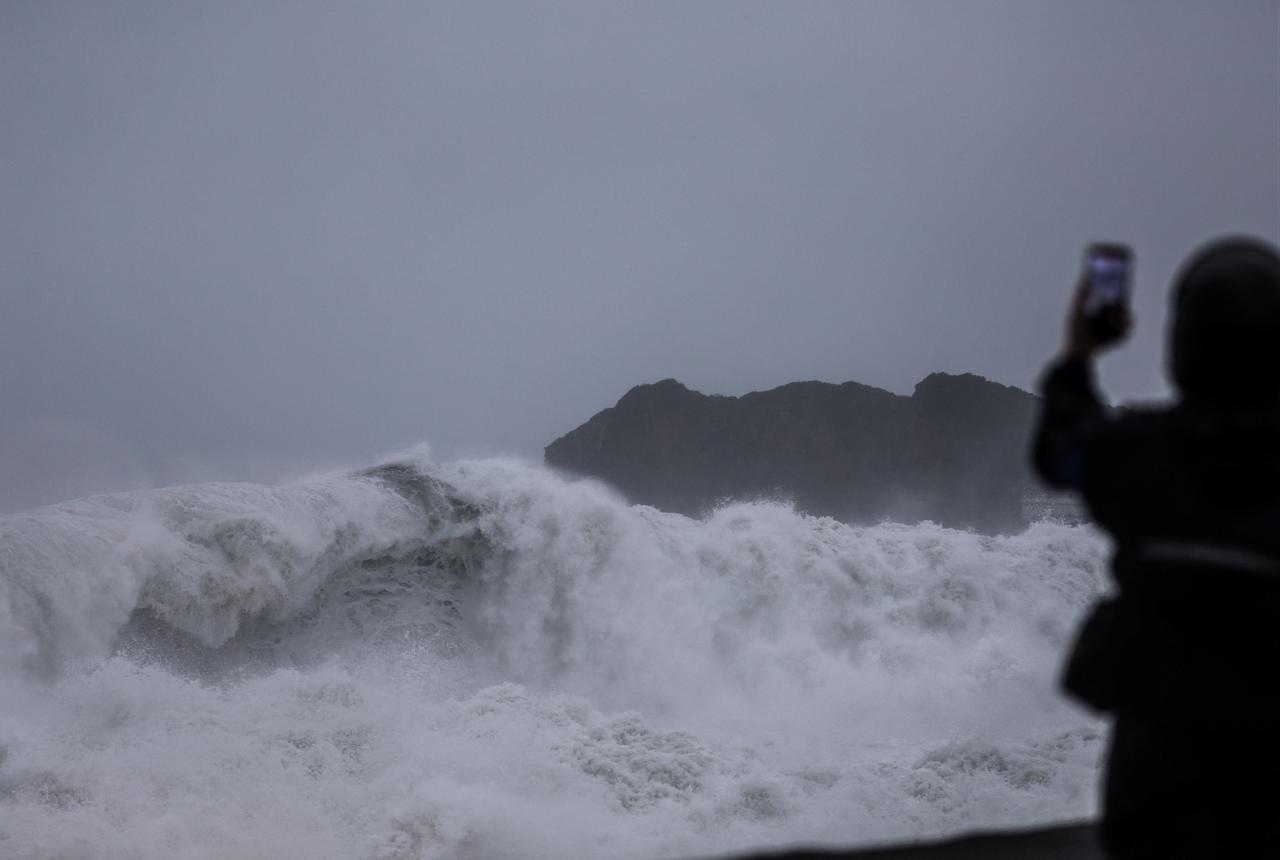 A person takes pictures of waves as Typhoon Champi approaches Taiwan, in Keelung on October 23, 2026. (AFP Photo)