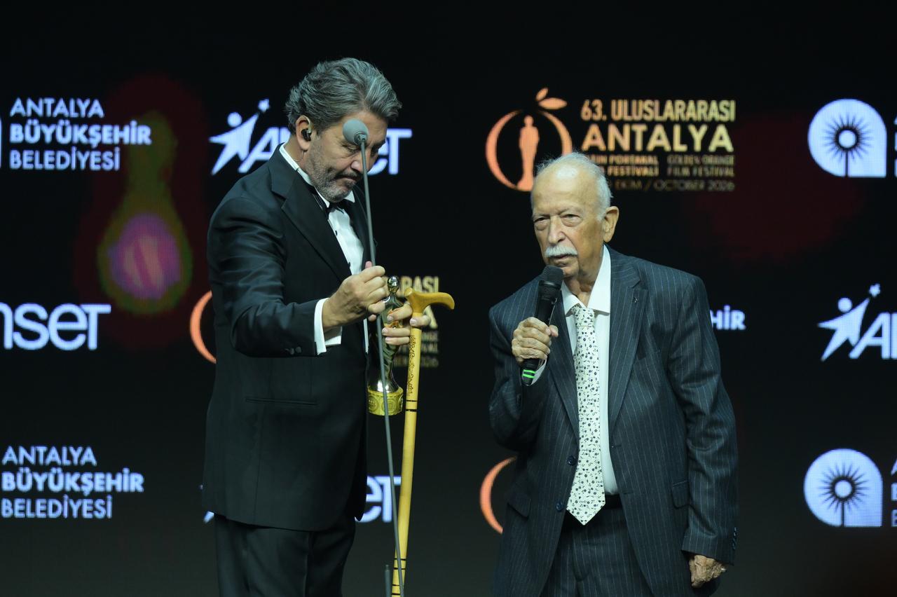 Producer Abdurrahman Keskiner (right) receives the "Labor Award" on stage during the opening ceremony of the 63rd International Antalya Golden Orange Film Festival at the Antalya Sports Hall, hosted under the theme "ALWAYS" by the Antalya Metropolitan Municipality. (AA Photo)