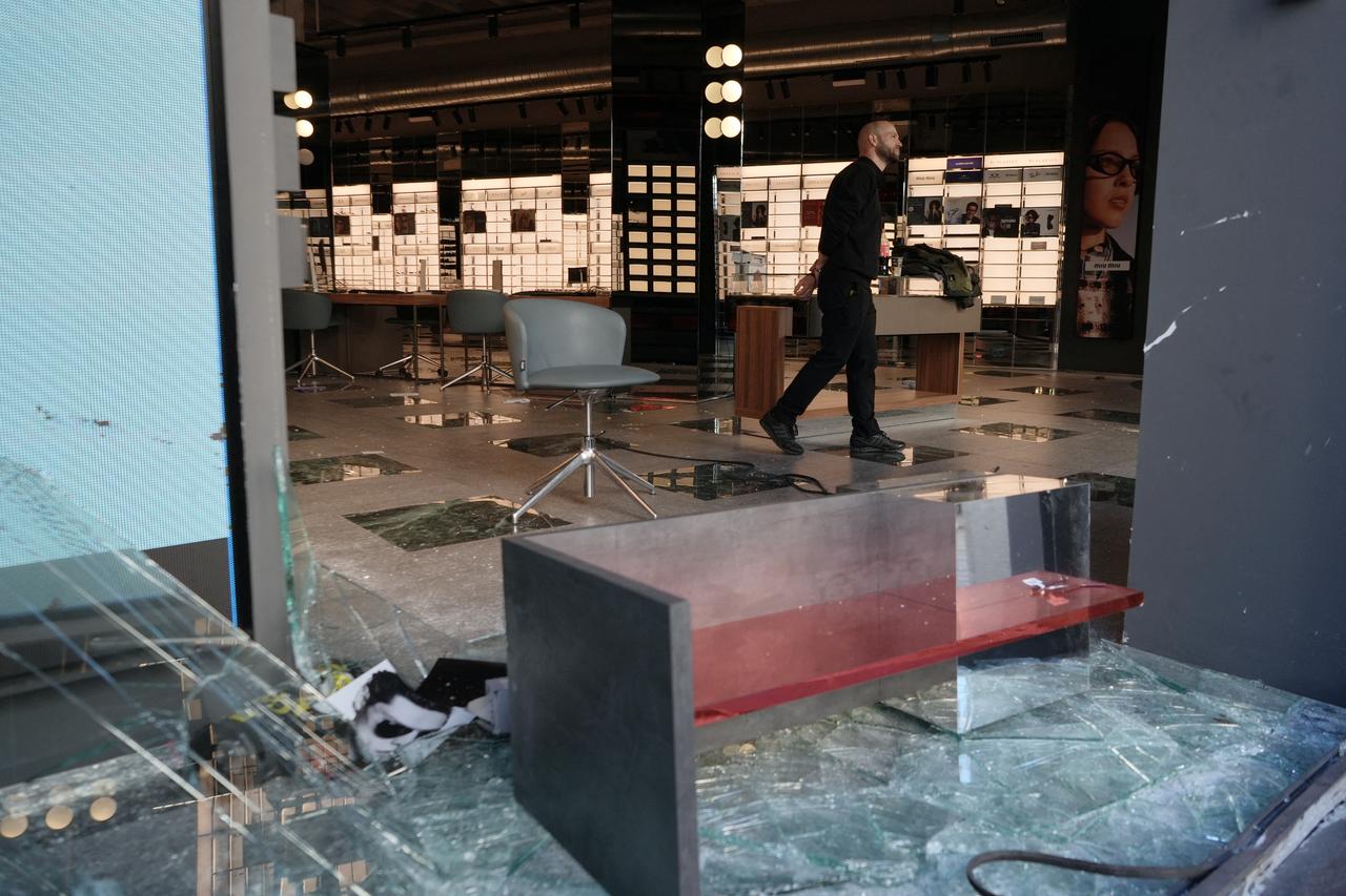 An employee inspects an optician's shop looted the previous night during riots, in Barcelona on Oct. 25, 2026. (AFP Photo)