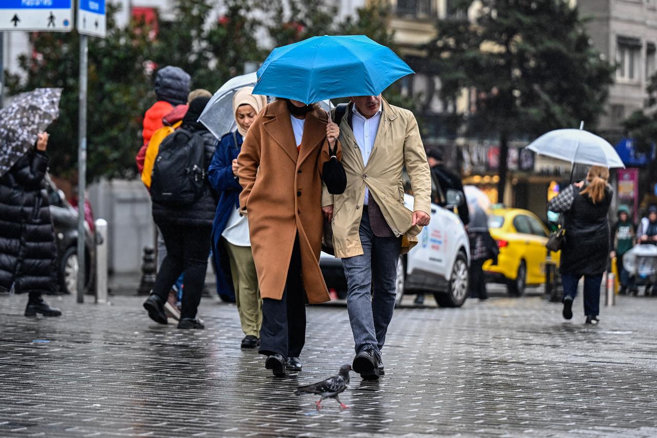 People use umbrellas to shield themselves from intermittent rainfall on Istiklal Street in Istanbul, Turkiye, on Oct. 15, 2026. (AA Photo)