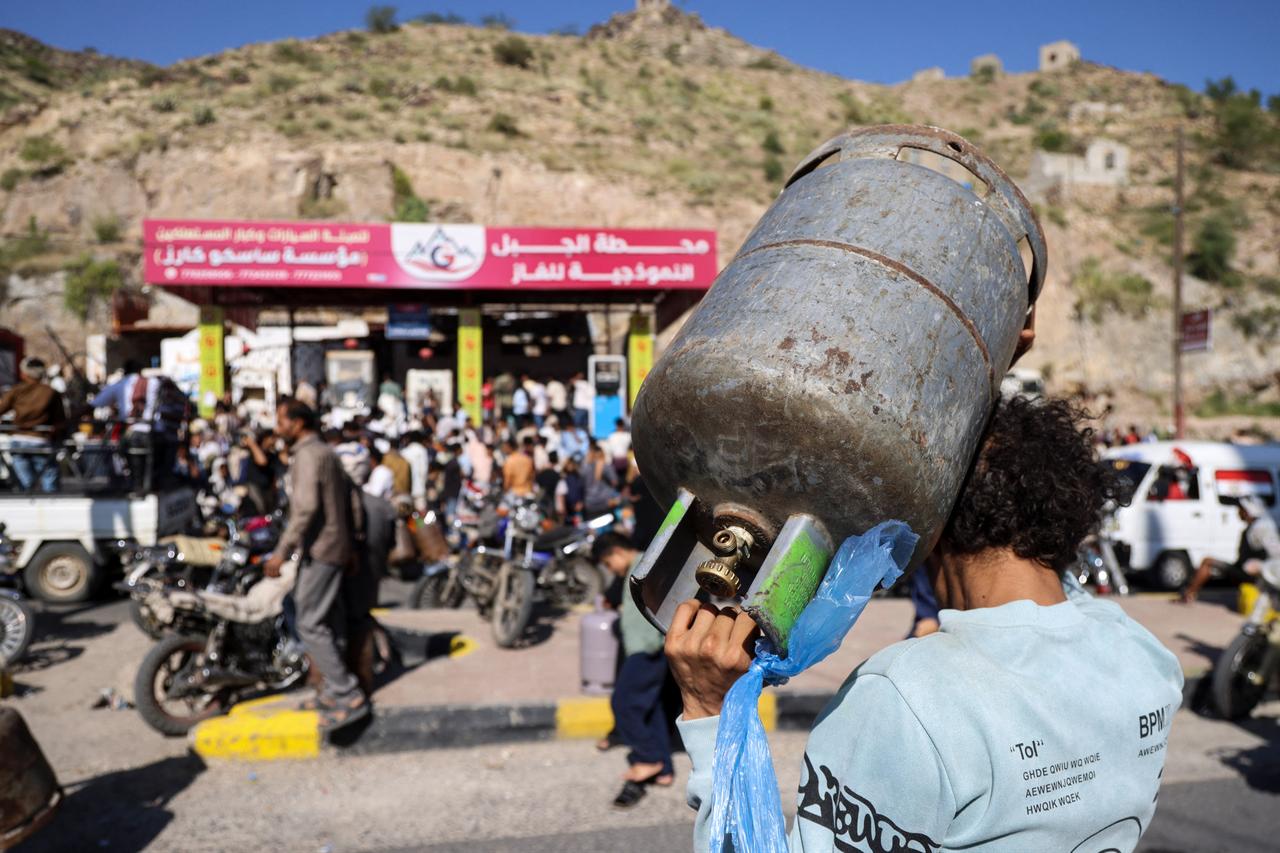 A Yemeni man carries a gas bottle as he waits with others to refill it at a refilling station in Taiz on Oct. 19, 2026. (AFP Photo)