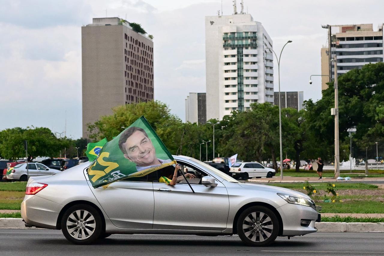 Supporters of Brazil’s right-wing Senator and presidential candidate Flavio Bolsonaro wave a flag with his picture from a car in Brasilia on Oct. 24, 2026, ahead of the presidential election runoff. (AFP Photo)