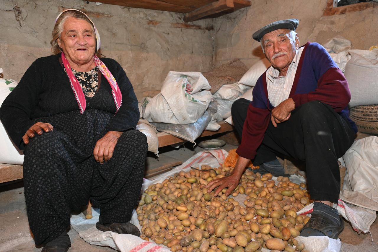 An elderly couple married for 57 years sits beside a pile of harvested potatoes in a storage room at their village home in Osmaniye, Türkiye, Oct. 25, 2026. (AA Photo)