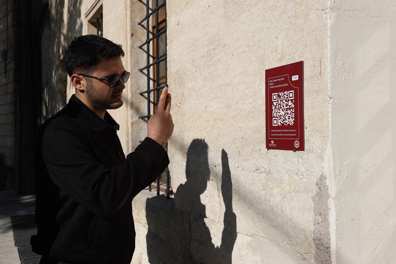 Visitors scan QR code plaques installed on historical landmarks in Cappadocia, connecting physical sites to an online database detailing their architectural history. (AA Photo)