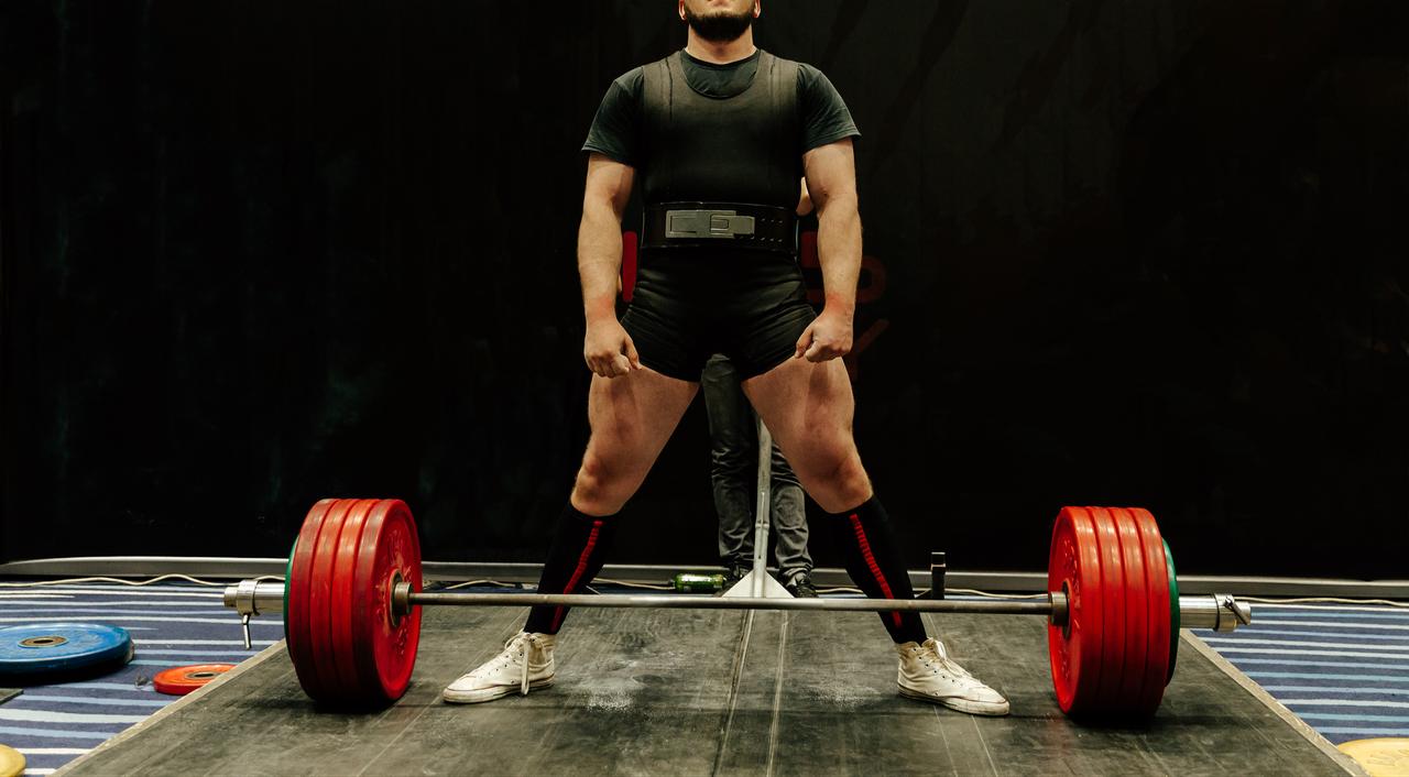 A powerlifter prepares to lift a loaded barbell during a weightlifting session. (Adobe Stock Photo)