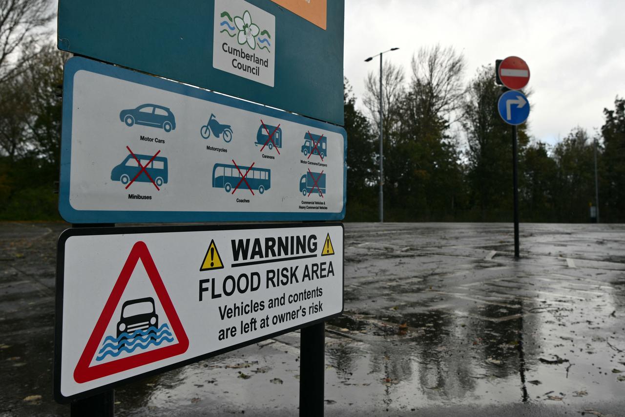 A flood risk warning sign stands beside a waterlogged parking area in Cumbria, England, Oct. 25, 2026. (AFP Photo)