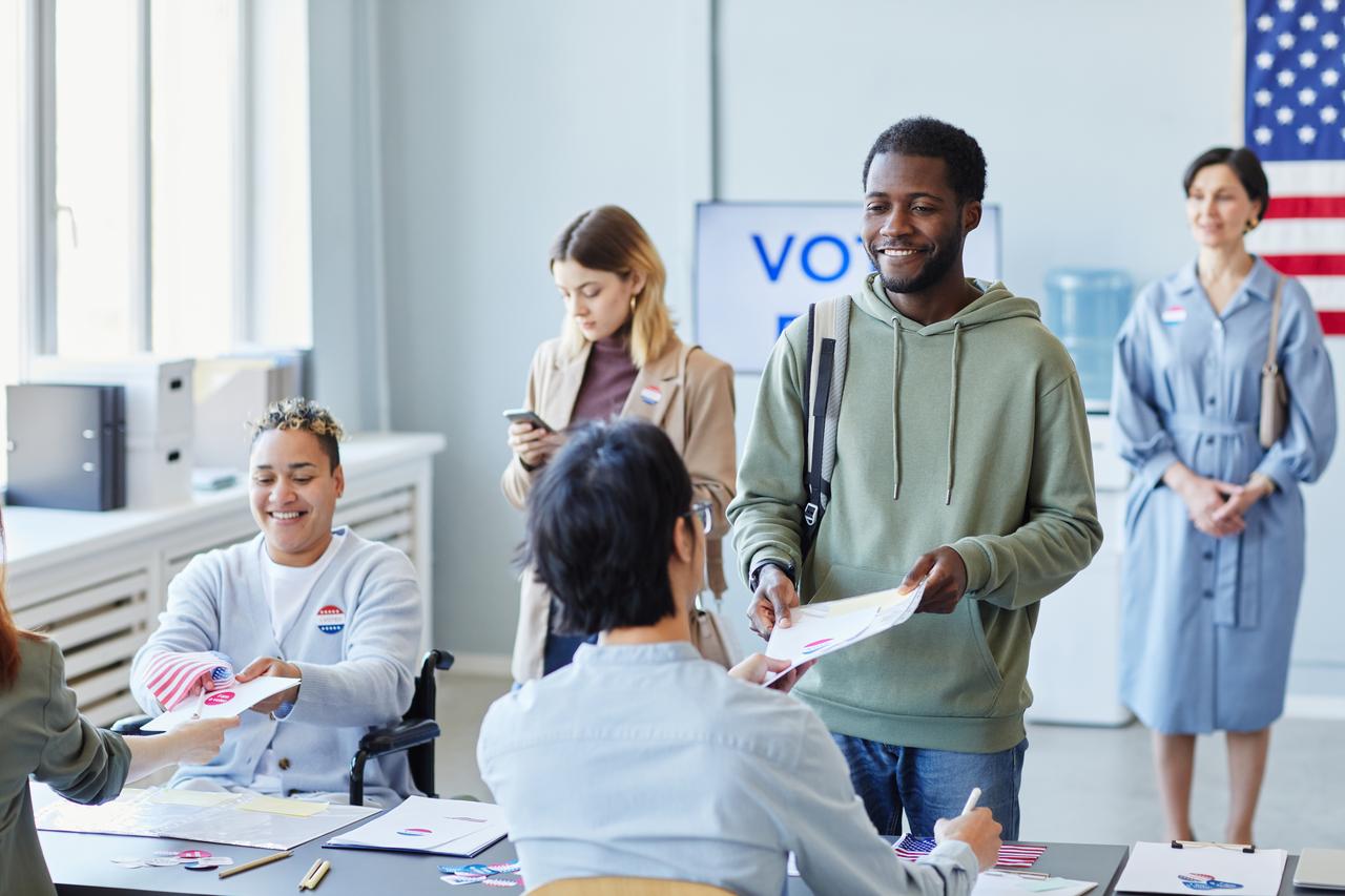 Voters receive ballots and election materials from poll workers at a polling station in the United States. (Adobe Stock Photo)