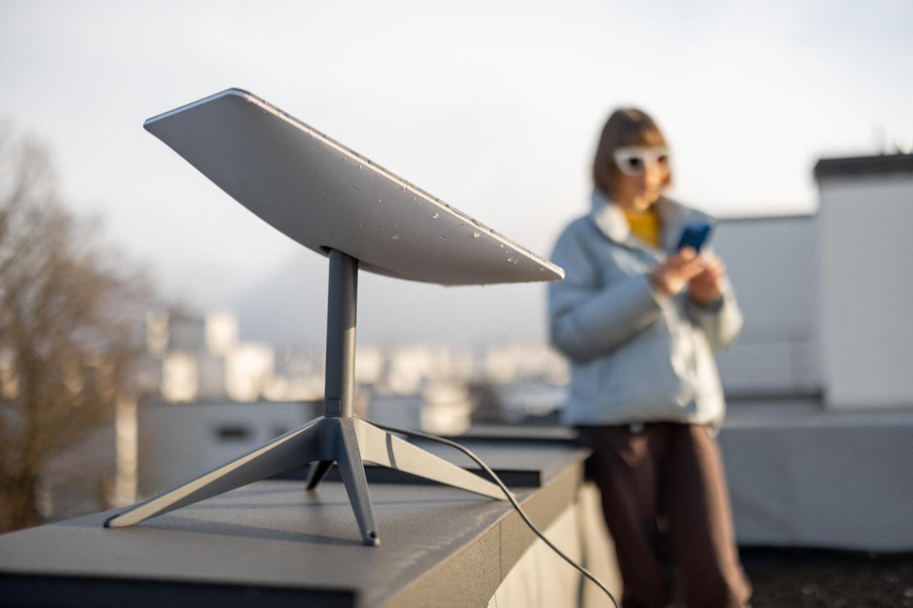 A woman uses her smartphone beside a Starlink satellite dish in Lviv, Ukraine, in January 2023. (Adobe Stock Photo)