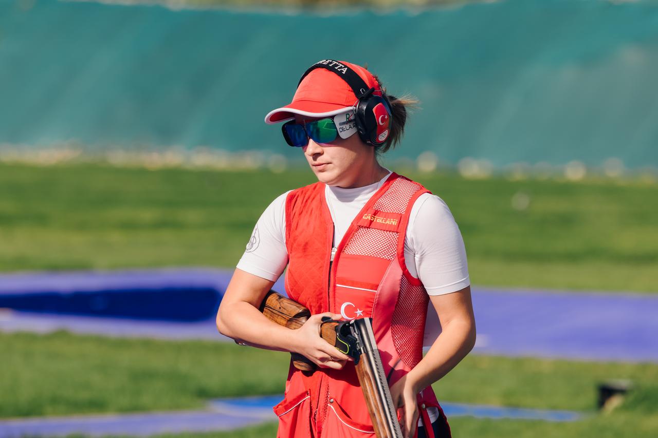 Turkish shooter Rumeysa Pelin Kaya stands in position, holding her open shotgun, wearing glasses and protective gear. (Photo via European Shooting Confederation)