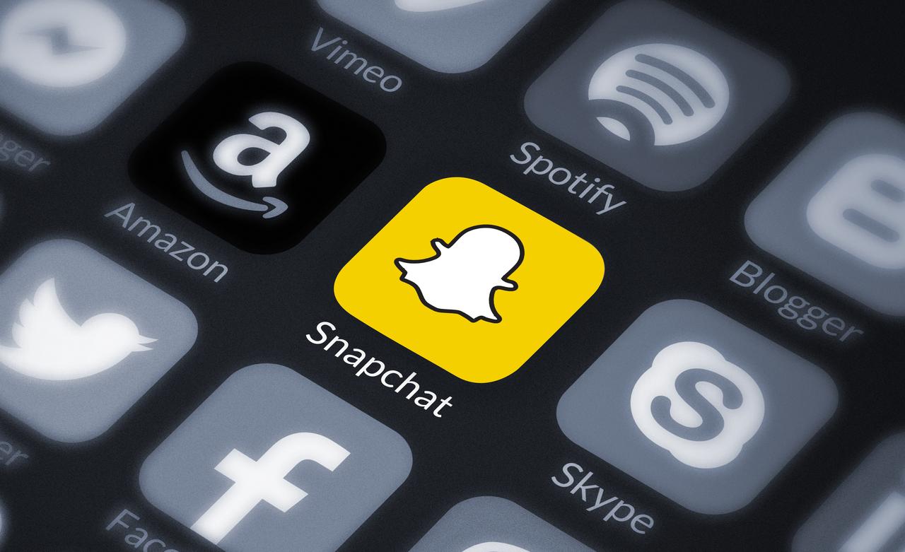 Snapchat logo colored on a black-and-white phone screen. (Photo via Adobe Stock)
