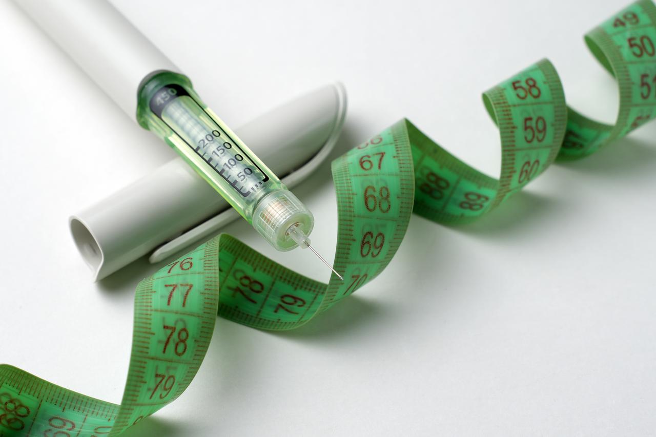 An injectable medication pen is pictured alongside a measuring tape, illustrating weight management and weight-loss treatments. (Adobe Stock Photo)