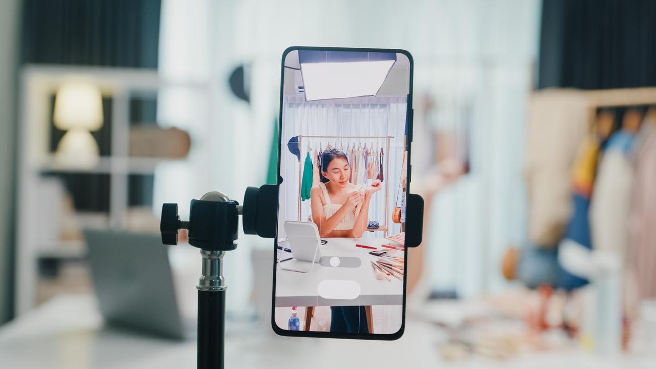 A smartphone is used to livestream a fashion and beauty presentation, illustrating social media-driven shopping and influencer marketing. (Adobe Stock Photo)