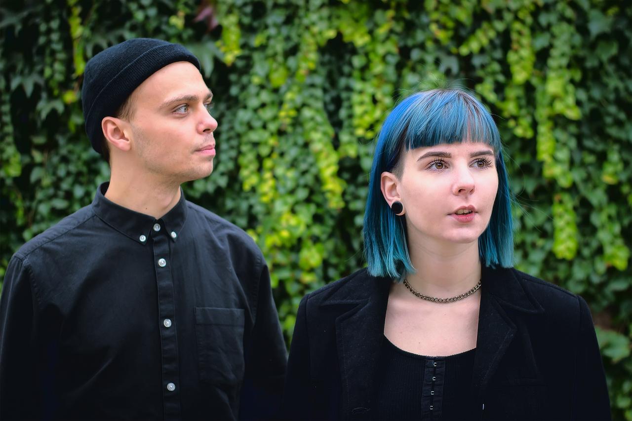 Two young people wearing alternative-style clothing and hairstyles stand outdoors, illustrating fashion and identity among younger generations. (Adobe Stock Photo)