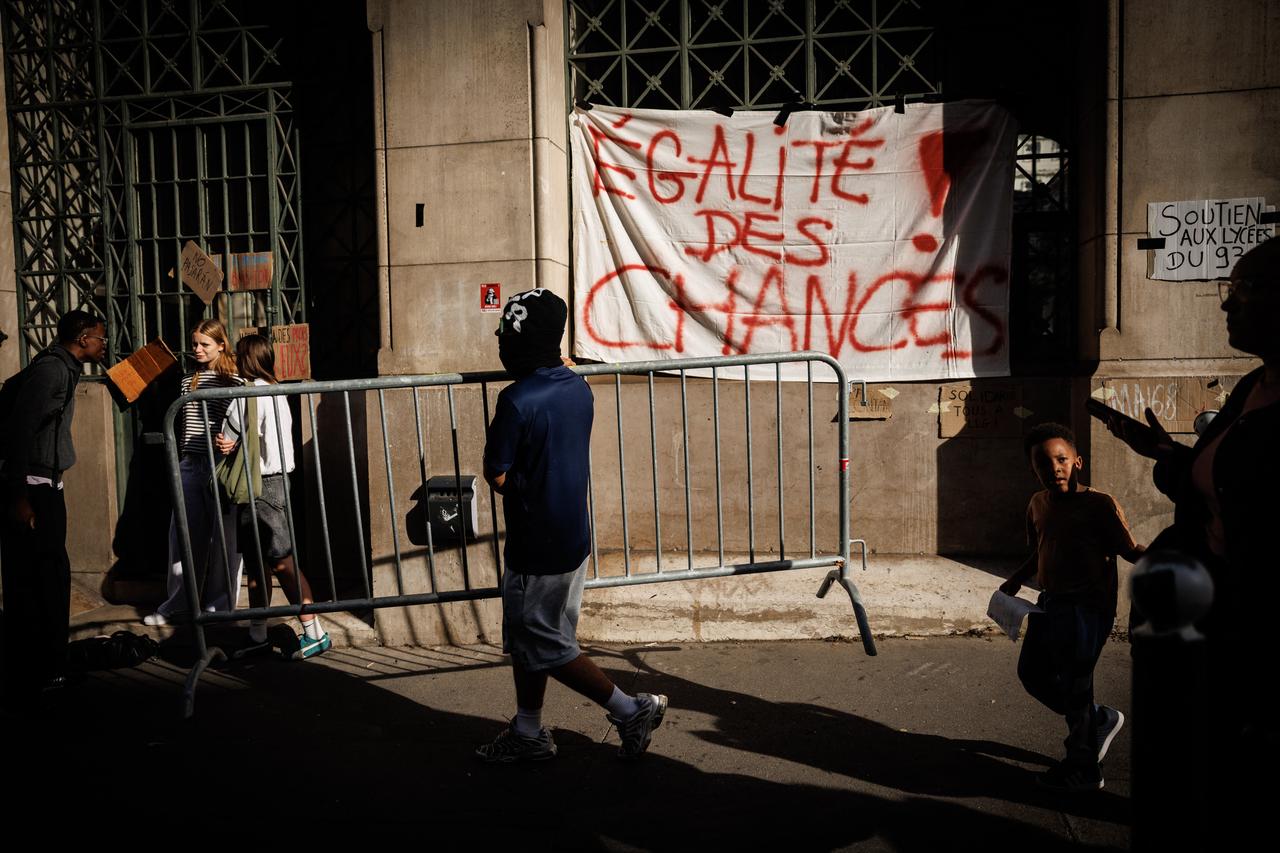 A student carries a barrier in front of a banner which reads "equal opportunities" suspended on the front of Louis-le-Grand high school in central Paris, on October 2, 2026. (AFP Photo)
