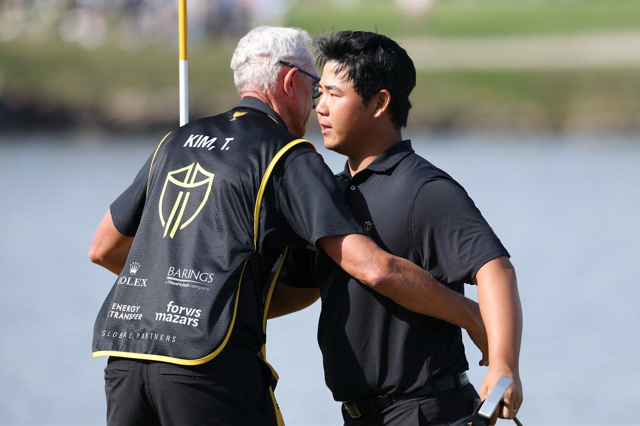 Tom Kim of South Korea and the International Team reacts with his caddie David Brooker after their 3&2 win on the 16th green during Sunday's Singles on day four of the Presidents Cup 2026 at Medinah Country Club on September 27, 2026 in Medinah, Illinois. (AFP Photo)