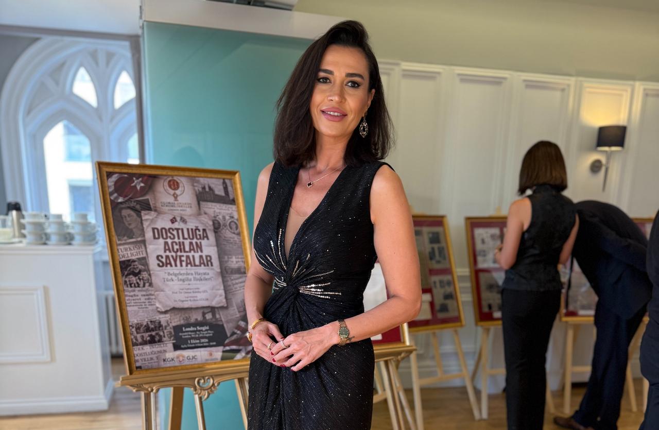 Exhibition curator Ozgenur Reyhan Guler poses beside the promotional display for the "Pages Opening to Friendship" exhibition at Arundel House in London. (Photo via Ozgenur Reyhan Guler's Archive)