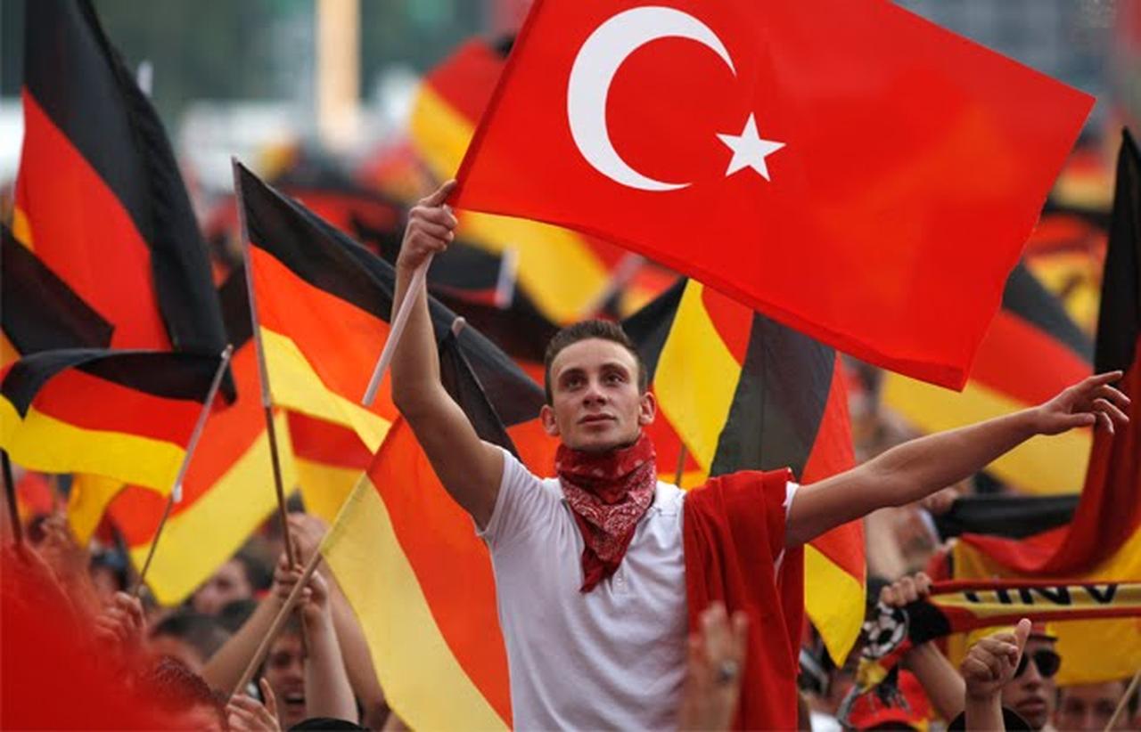 A young man waves the Turkish flag amid a crowd holding German flags. (Photo via matthewbrunwasser.com)
