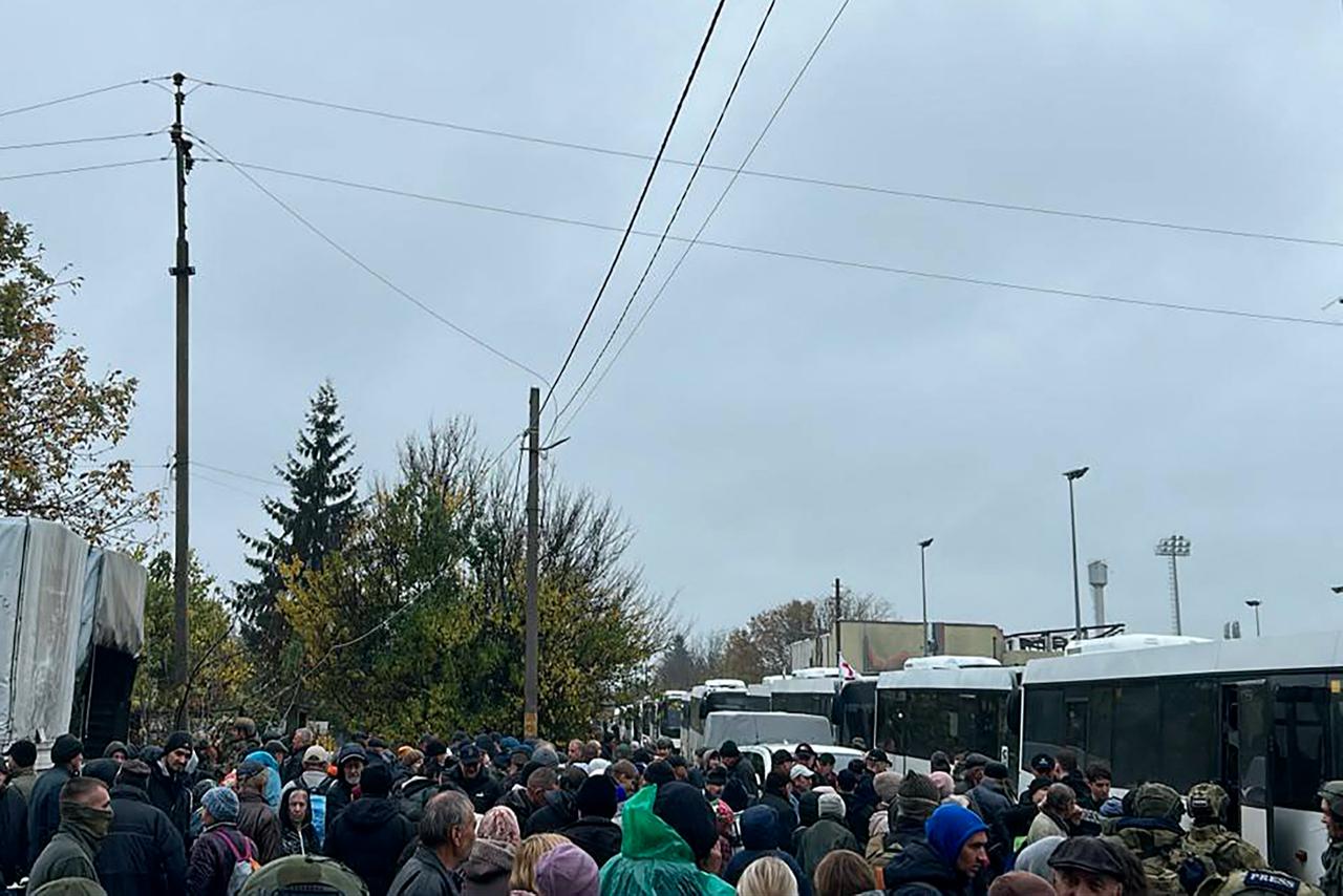 In this handout photograph posted on October 30, 2026, local residents wait next to buses ahead of their evacuation in Oleshky, Kherson region. (AFP Photo/Handout/Telegram/ @David_Arakhamia)