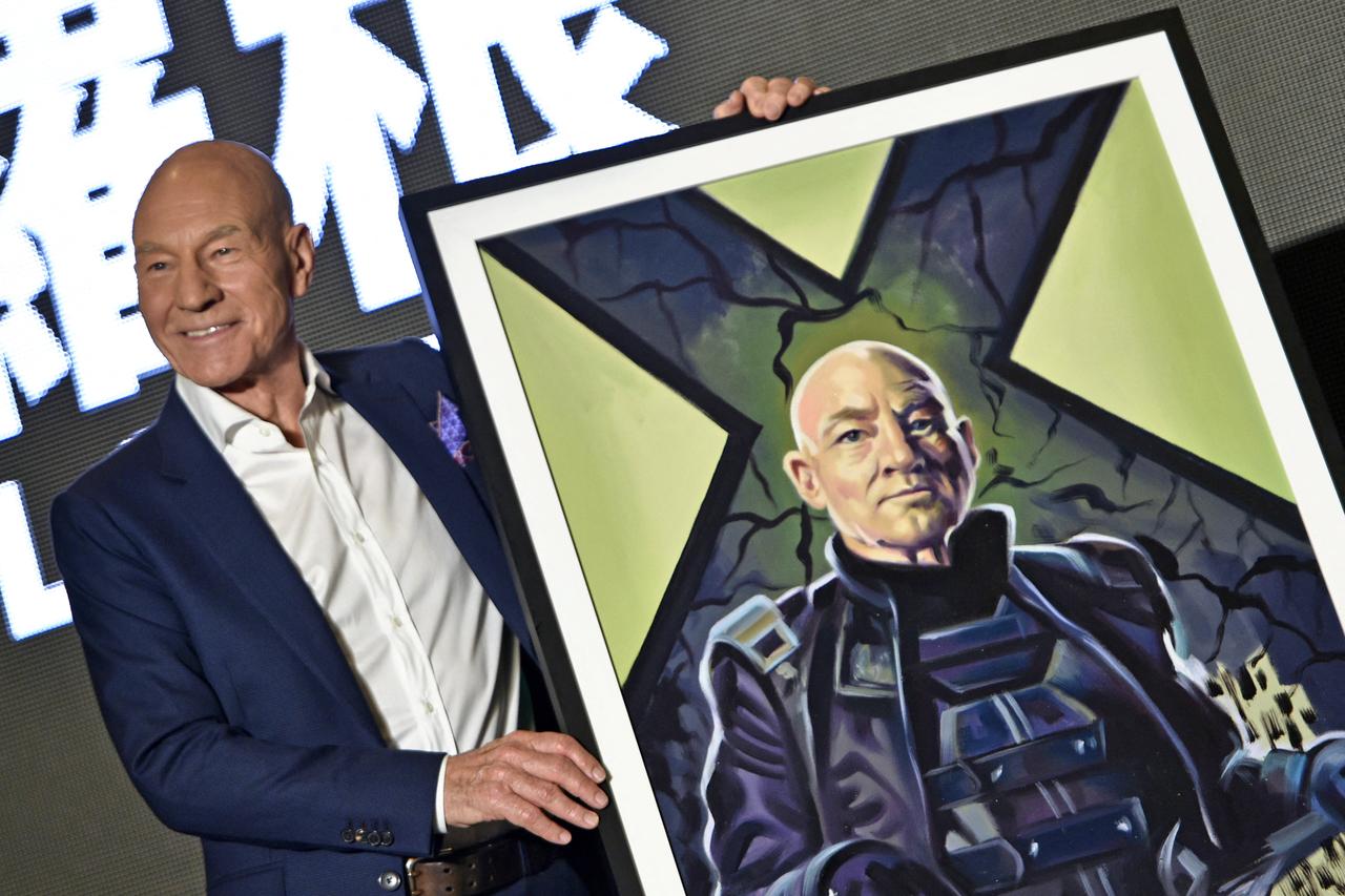 "Professor X" in the X-Men series' Patrick Stewart poses for photos with a gift of a painting during a press conference for the film "Logan" in Taipei on February 28, 2017. (AFP Photo)