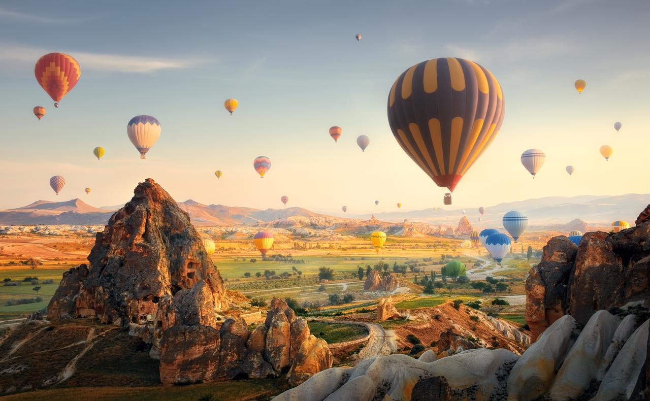 Hot air balloons flying over spectacular Cappadocia, Türkiye. (Adobe Stock photo)