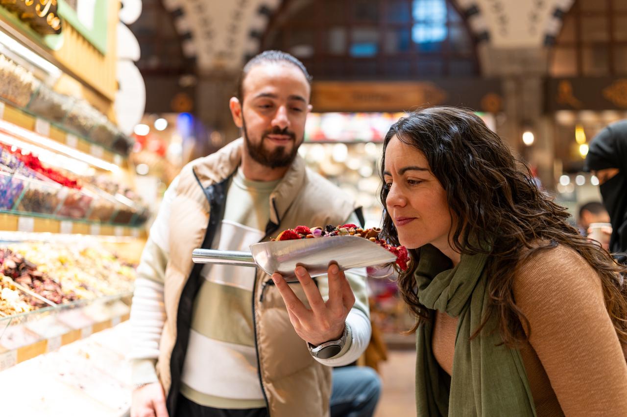 A tourist smelling dried fruits in the Istanbul spice market bazaar. (Adobe Stock photo)