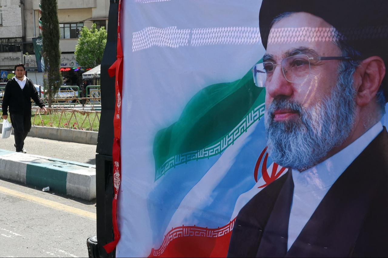 A man walks past a banner depicting Iran's new supreme leader Mojtaba Khamenei, along a street in Tehran on April 5, 2026. (AFP Photo)