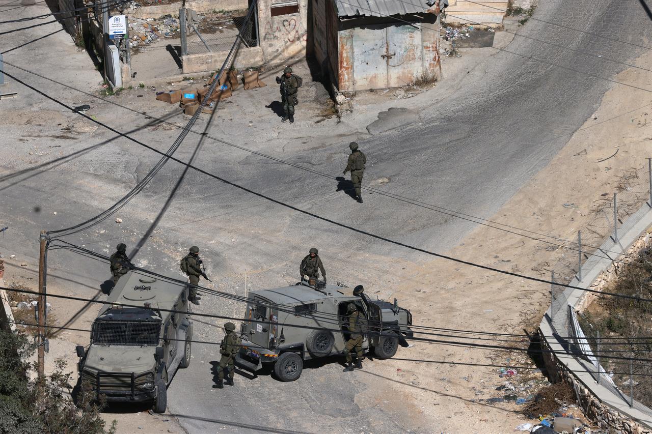 Israeli soldiers take position during an operation to demolish the homes of the two Palestinian gunmen who killed two Israeli soldiers at a West Bank checkpoint the previous week, in the Israeli-occupied West Bank city of Hebron, on October 30, 2026. (AFP Photo)