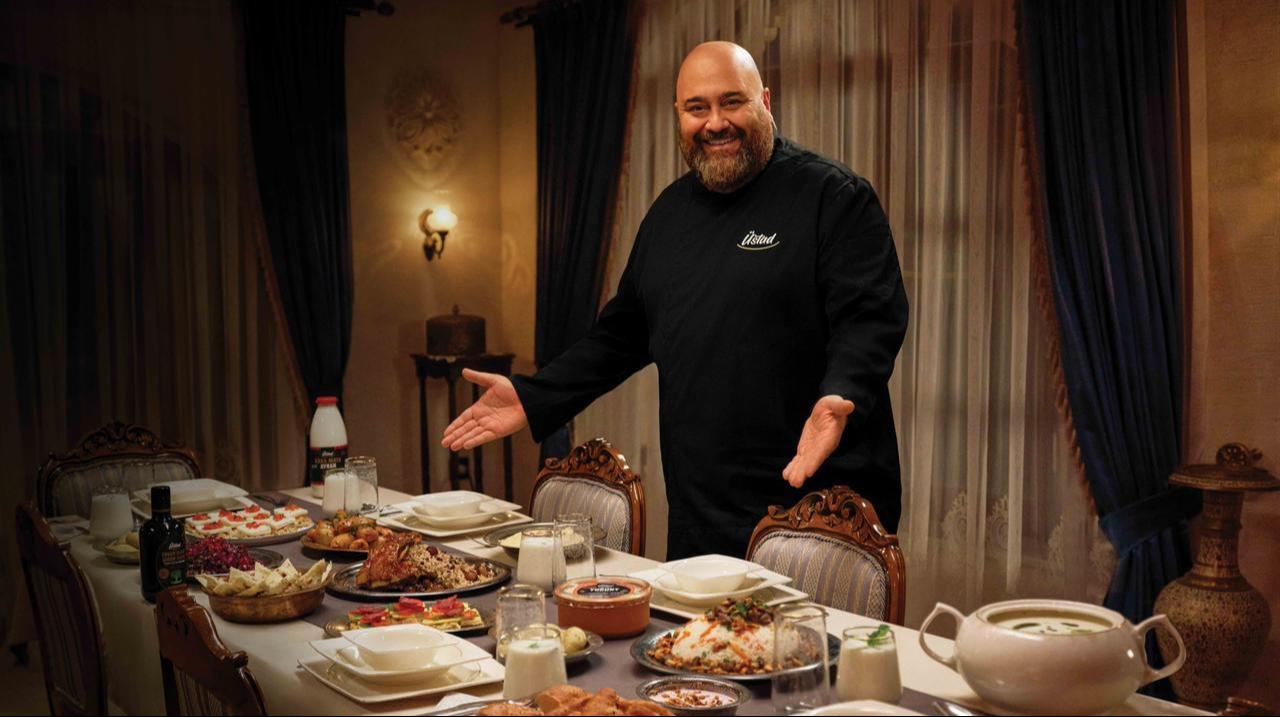 Turkish celebrity chef Somer Sivrioglu poses beside a dining table featuring a selection of dishes during a promotional shoot. (IHA Photo)