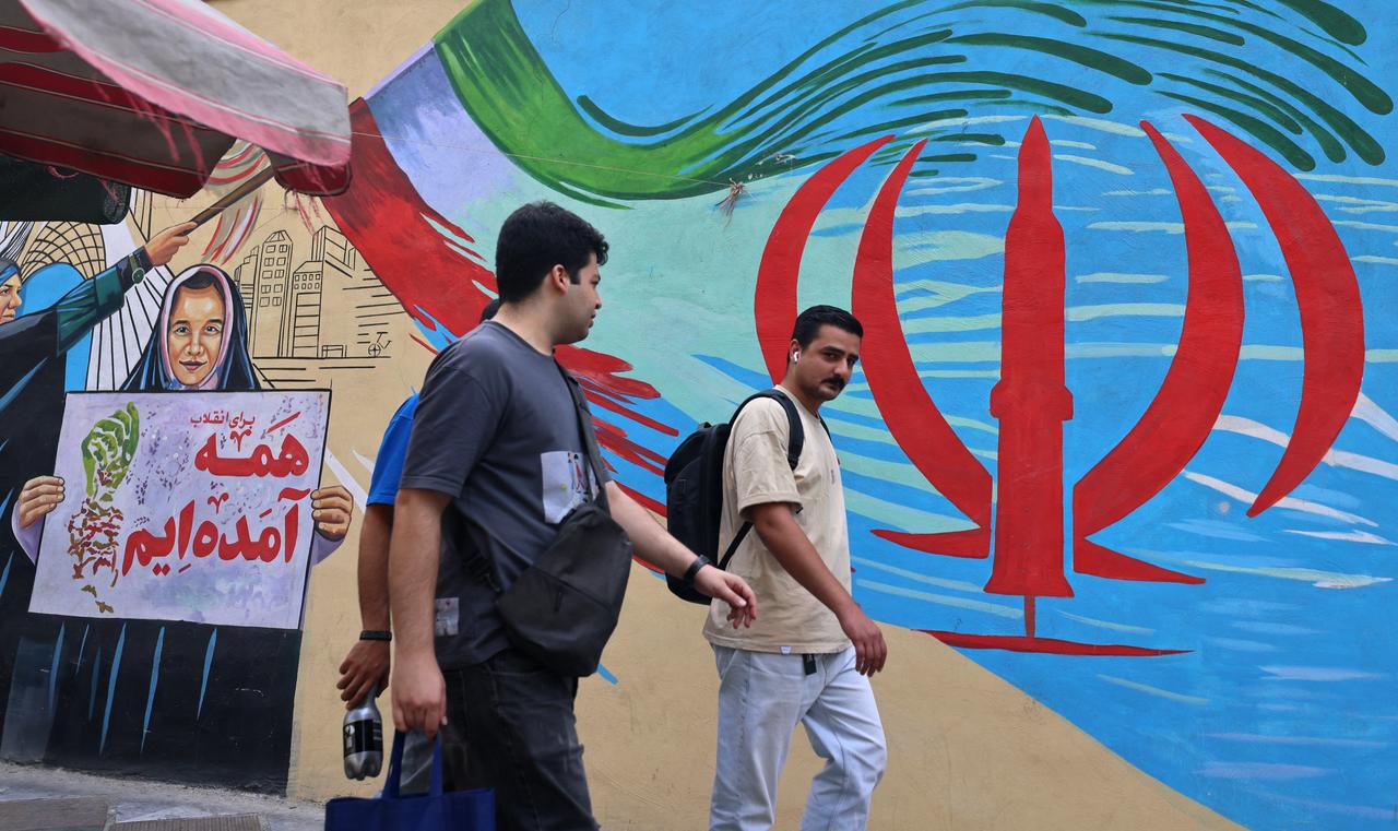Pedestrians walk past a wall mural along a street in downtown of Tehran on August 31, 2026. (AFP Photo)