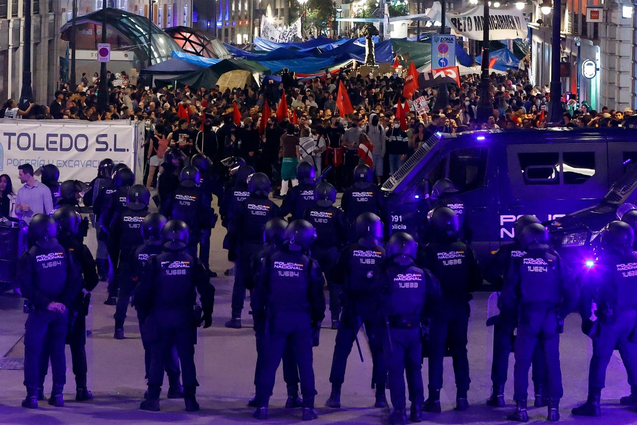 Police officers stand guard on one of the streets leading to Puerta del Sol Square where people camp in tents to protest against evictions and the housing crisis, in Madrid on October 3, 2026. (AFP Photo)