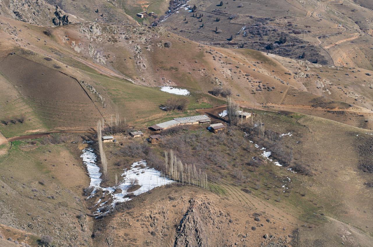 A rural settlement lies among rugged highlands with patches of lingering snow in Türkiye. (Adobe Stock Photo)