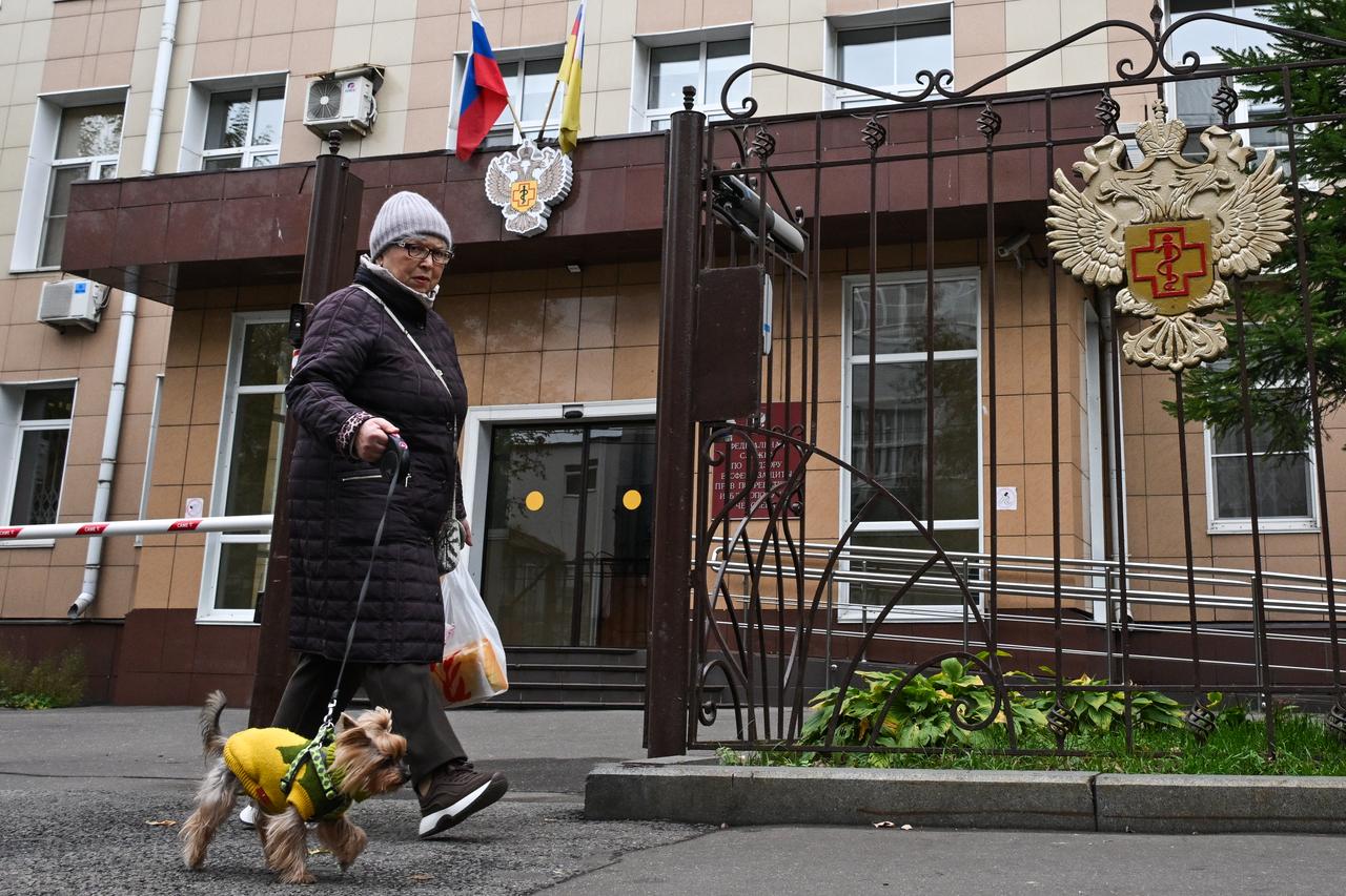 A woman walks a dog past the headquarters of Russia's consumer and health watchdog Rospotrebnadzor in Moscow on October 5, 2026. (AFP Photo)