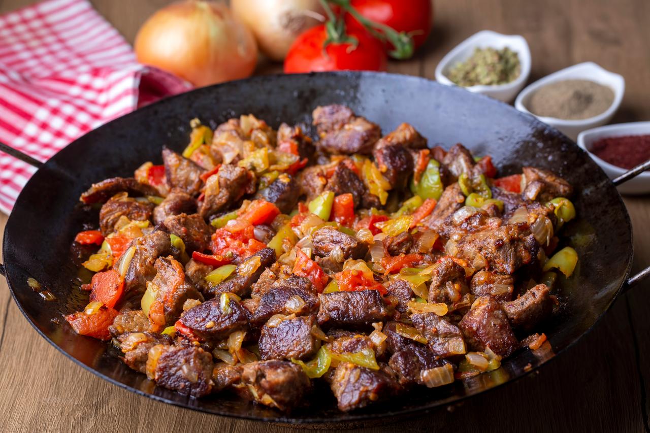 Coban kavurma, a traditional Turkish lamb dish, combines browned meat with sauteed onions, tomatoes and peppers in a wide iron pan. (Adobe Stock Photo)