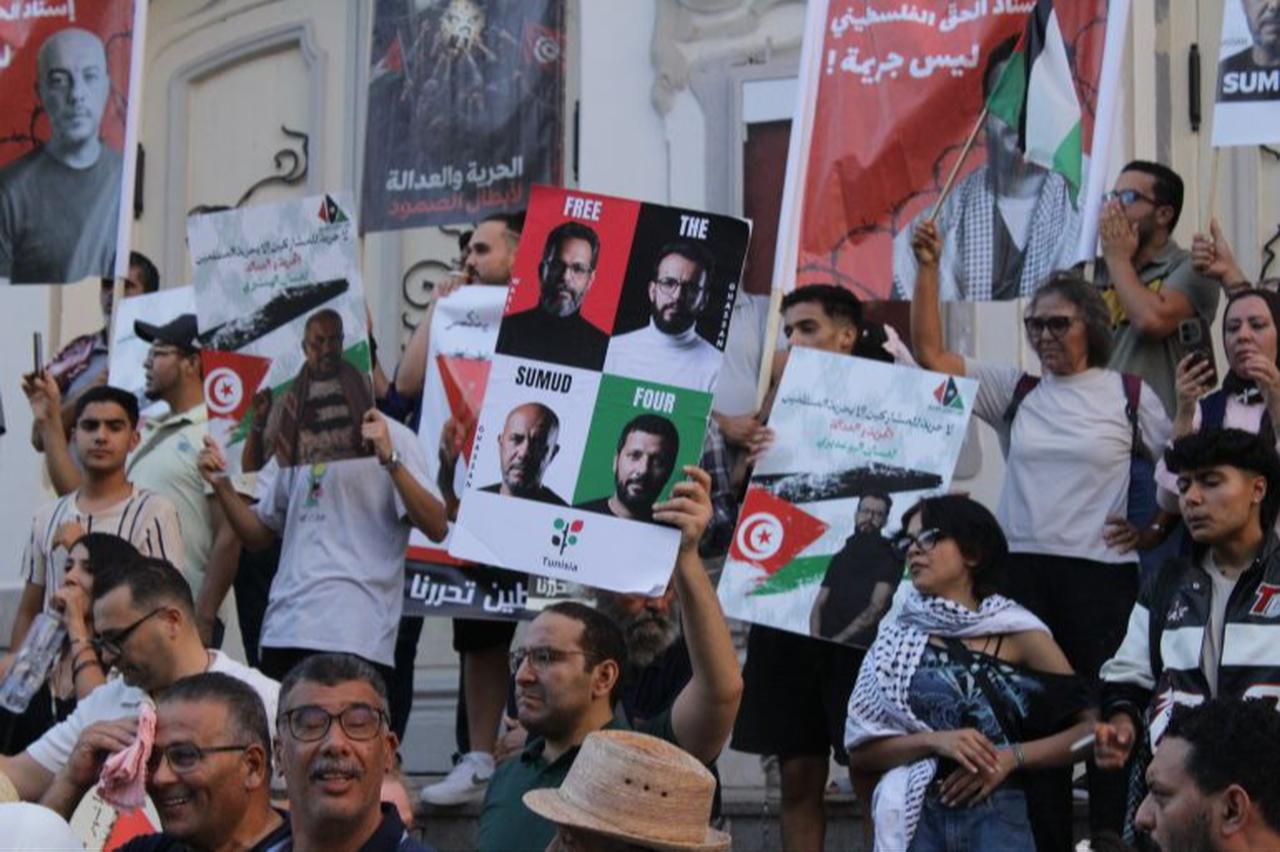 Protesters hold up a sign reading “Free the Sumud Four,” with portraits of the four jailed activists, at a demonstration on Sept. 19, 2026, in Tunis. Another sign reads, in Arabic, “Supporting the Palestinian cause is not a crime.” (Photo via aljazeera.com)