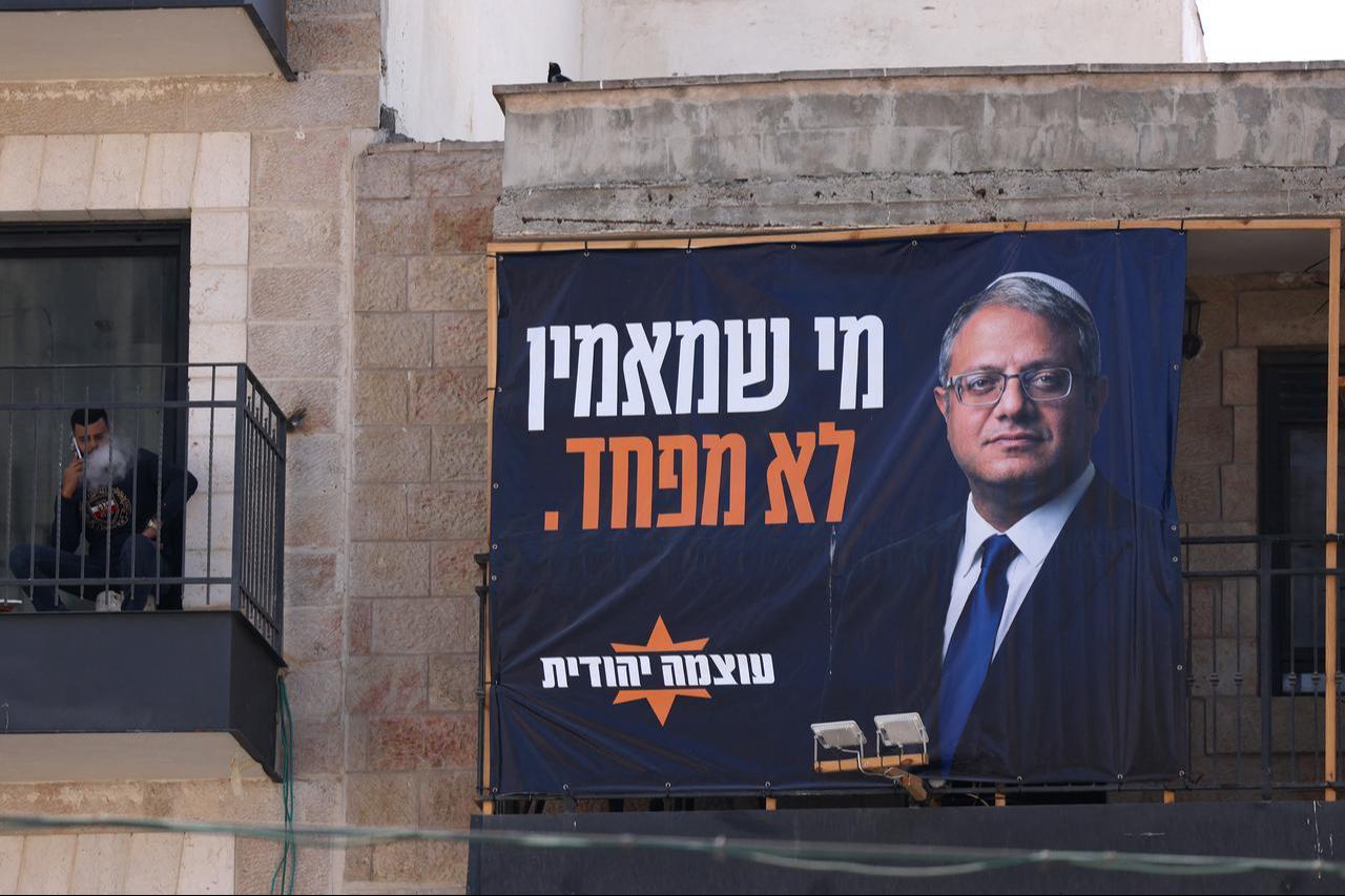 A man speaks on his mobile while sitting in a balcony next to an election billboard bearing a portrait of Otzma Yehudit (Jewish Power) party leader Itamar Ben Gvir, in Jerusalem, Oct. 4, 2026. (AFP Photo)