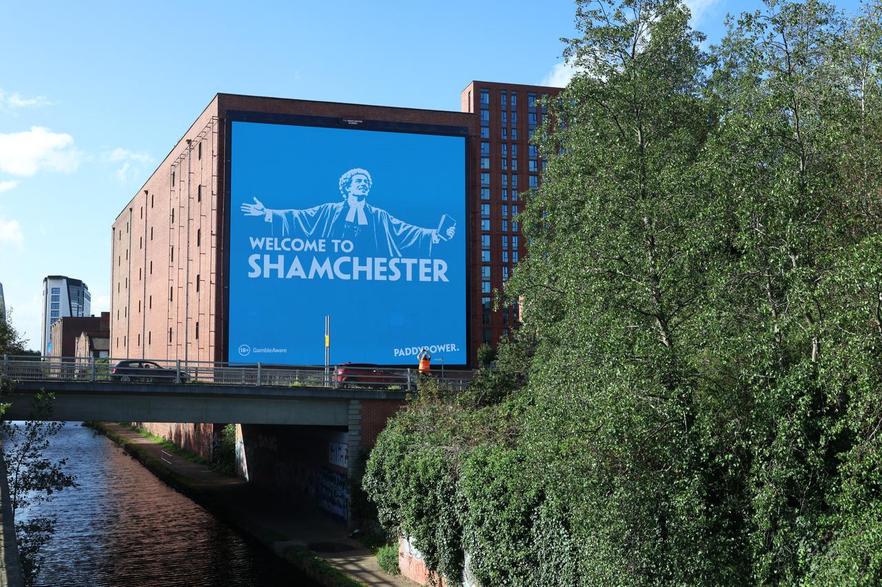 A large “Welcome to Shamchester” billboard is displayed beside a canal in Manchester, England, Oct. 1, 2026. (AFP Photo)