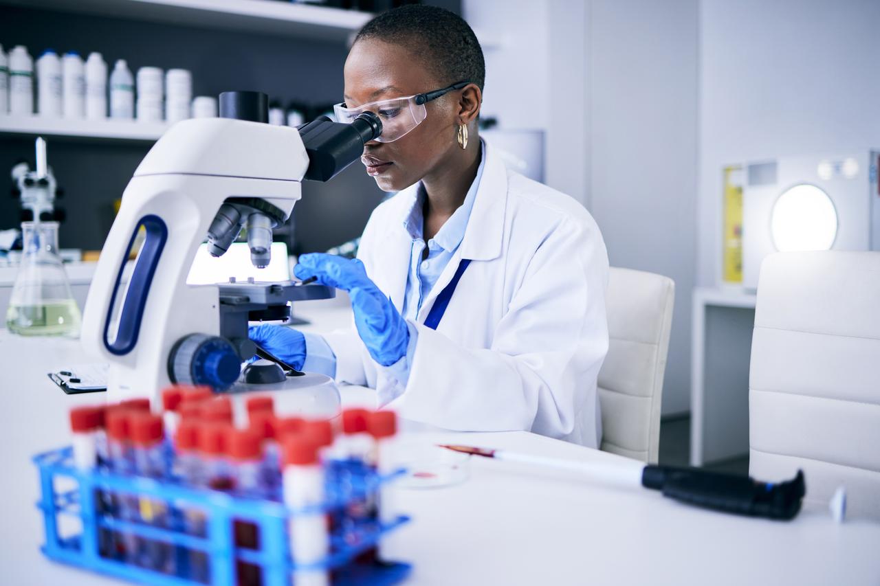 A scientist examines a sample through a microscope in a laboratory. (Adobe Stock Photo)