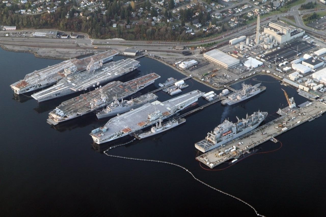 An aerial view shows decommissioned aircraft carriers USS Independence, USS Kitty Hawk, and USS Constellation moored alongside other naval vessels at the Puget Sound Naval Shipyard and Intermediate Maintenance Facility in Bremerton, Washington, on Nov. 24, 2012. (Photo courtesy of Wikimedia Commons)