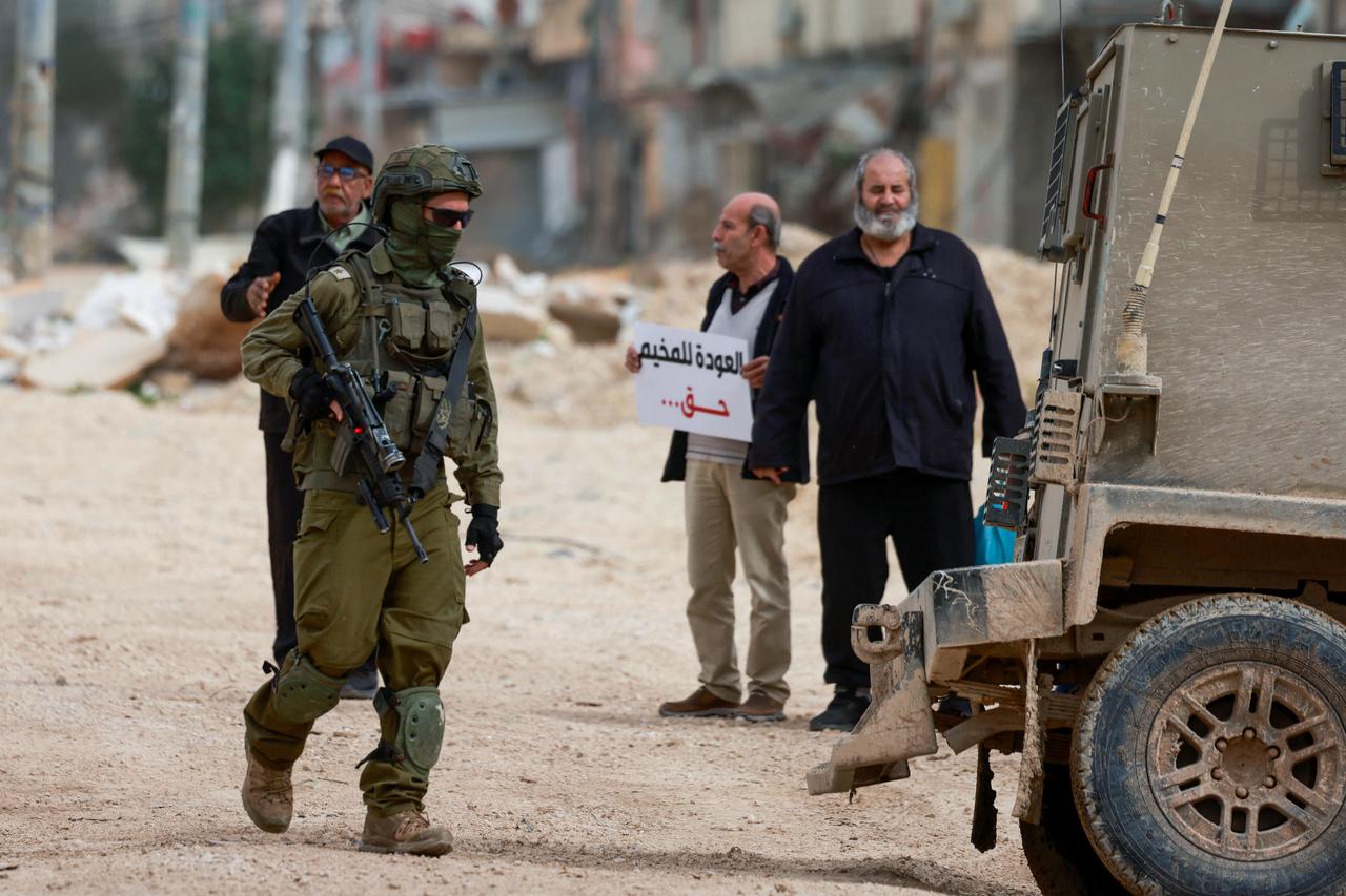 An Israeli soldier walks near Palestinians protesting after Israeli security forces blocked the entrance of the Nur Shams Palestinian refugee camp in occupied West Bank, Feb. 9, 2026. (AFP Photo)